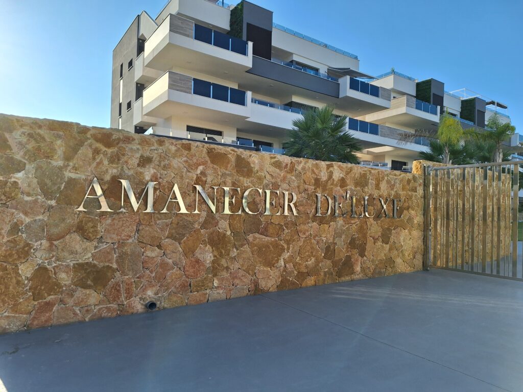 Kamienne wejście z napisem Amanecer Deluxe na terenie osiedla